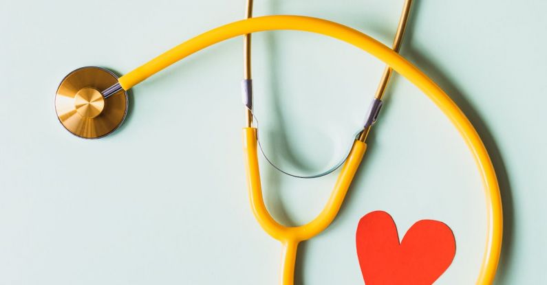 Heart Disease - Medical stethoscope with red paper heart on white surface