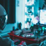 Reality TV Shows - Side view of unrecognizable person in virtual reality helmet sitting on sofa and playing with gamepad in dark room