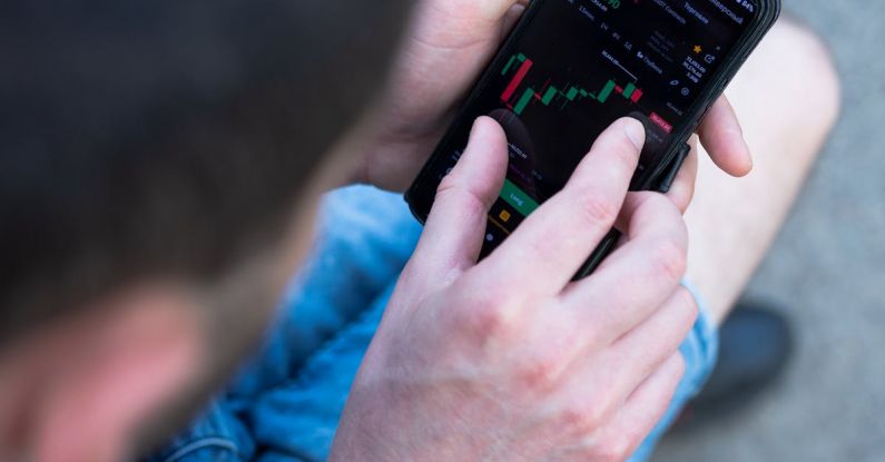 Financial Habits - A man is using his cell phone to look at the stock market