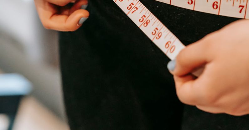 Fitness Regimens - From above of crop anonymous plump female using measuring tape around hips in gym