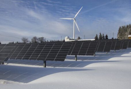 Renewable Energy - Solar Panels on Snow With Windmill Under Clear Day Sky