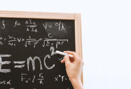 Quantum Physics - Person Holding a Chalk in Front of the Chalk Board