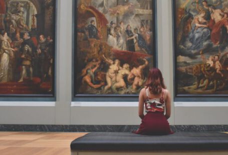 Museums - Woman Sitting on Ottoman in Front of Three Paintings