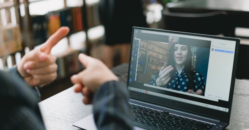 Language Preservation - Young lady learning sign language during online lesson with female tutor