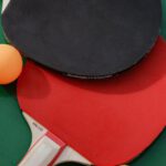 Sports Merchandising - Two ping pong paddles and two balls on a green table