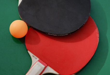 Sports Merchandising - Two ping pong paddles and two balls on a green table