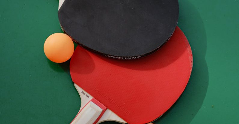 Sports Merchandising - Two ping pong paddles and two balls on a green table