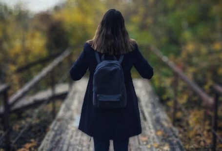 Solo Travel - Selective Focus Photography of Woman Wearing Black Overcoat Standing on Wooden Bridge