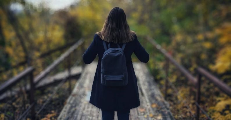 Solo Travel - Selective Focus Photography of Woman Wearing Black Overcoat Standing on Wooden Bridge