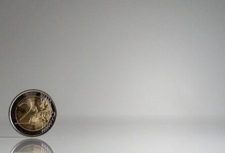 Financial Literacy - A coin on a white surface with a reflection