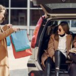 Mergers And Acquisitions - Young woman demonstrating shopping bags to friends