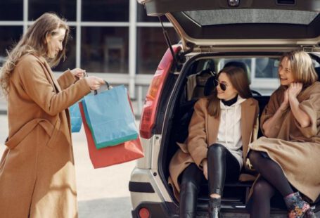 Mergers And Acquisitions - Young woman demonstrating shopping bags to friends